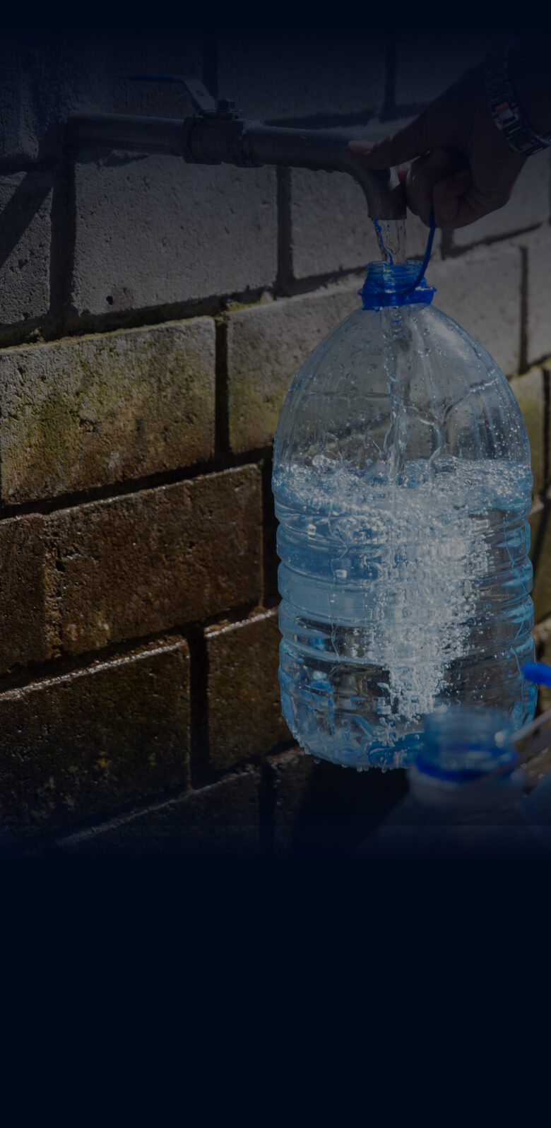 A person fills plastic water bottles at a tap highlighting the paradox of plastic.